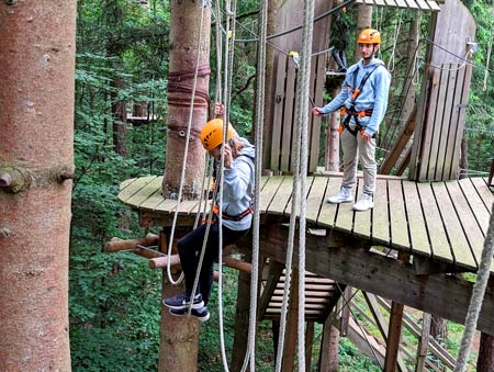 Teamwork im Fokus: Zwei PROXORA Mitarbeiter sichern sich gegenseitig über eine schwierige Passage im Hochseilgarten ab.